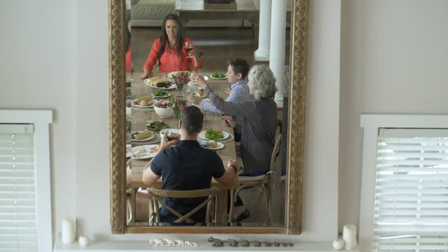 Mirror image of family dining together, making a toast.