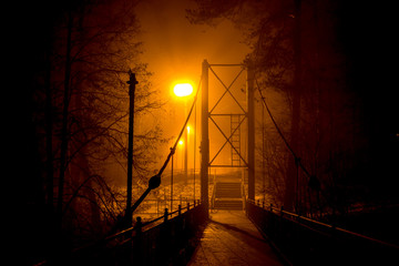 Pedestrian bridge in dense fog at night
