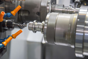 The CNC turning or lathe machine making the thread at the metal shaft with the tapping tool. High technology manufacturing concept.