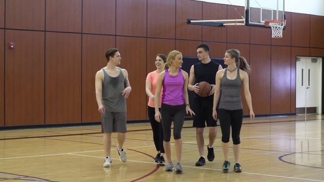 Young men and women walking on a basketball quart
