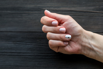 the manicure, pink with white color, isolated on a black wooden background