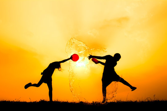 Silhouette of children playing water during sky sunset, Songkran Festival in Thailand and summer season