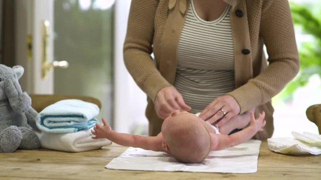 Mum changing baby's nappy, panning left.