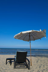 Beach loungers on the deserted coast sea at sunrise.