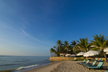 Beach loungers on the deserted coast sea at sunrise.