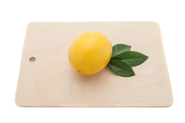 yellow bright lemon with three green leaves on a chopping board 