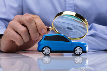 Person Holding Magnifying Glass Over Car