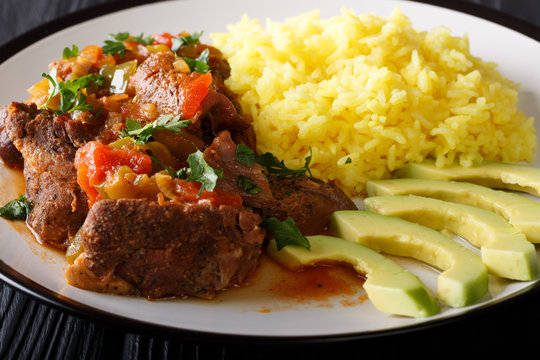 Seco de chivo is goat stew with yellow rice and fresh avocado close-up on a plate. horizontal