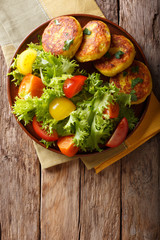 Freshly prepared potato pancakes are served with fresh salad close-up. Vertical top view