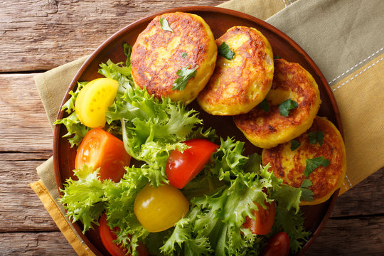 Delicious hot potato pancakes with fresh vegetable salad close-up. horizontal top view