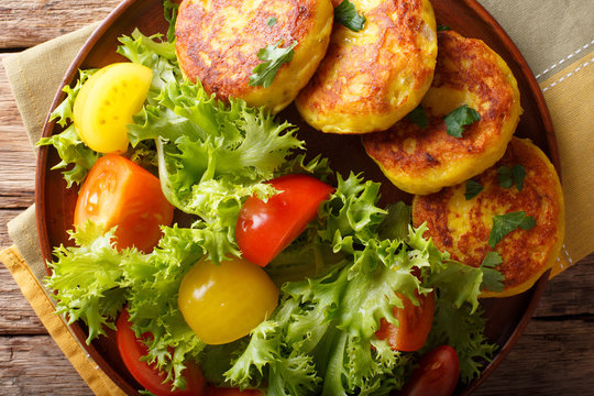 Ecuadorian potato pancakes llapingachos and fresh salad close-up on a plate. Horizontal top view