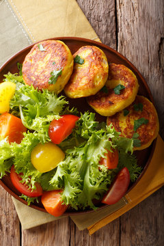 Delicious hot potato pancakes with fresh vegetable salad close-up. Vertical top view