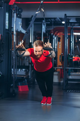 Fototapeta premium Strong woman using a resistance band in her exercise routine. Female athlete exercising with resistance band in studio.