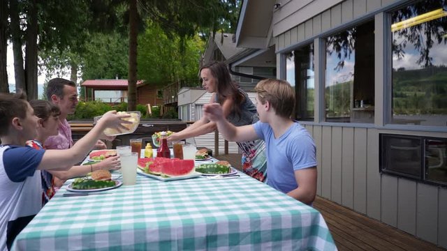 Family eating and drinking at table by lake house, Lake Connaught, Washington, USA.