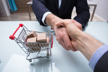 Close-up Of Two Businesspeople Shaking Hands Over Desk