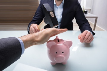 Businessman Stopping His Colleague From Breaking Piggybank