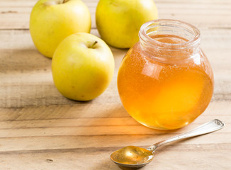 Apple jelly jar and spoon with granny smith apples on wooden table