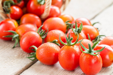 Small red cherry tomatoes spill out of a wicker basket.