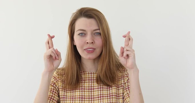 Portrait of young pretty woman worried with crossed fingers and closed eyes waiting for luck. Minded girl hoping for the best