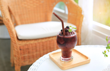 Glass of fresh blueberry smoothie on the wood table at the cafe.