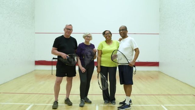 Four people standing on a squash court