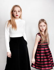 Isolated. The two young girls  with long hair are posing on the white wall