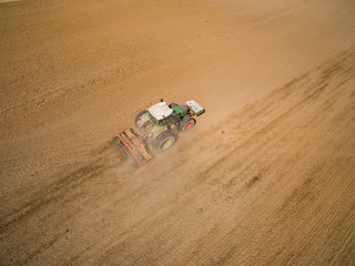 Fototapeta na wymiar Aerial: ractor plows a agricultural field in spring and prepares it for sowing - aerial view