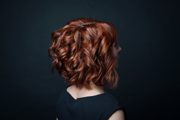 Hair bob with short curls on the female head with red hair side view against the background of black isolate. - 201456694