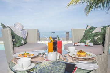 Fresh breakfast setup juice and coffee on table next to the pool