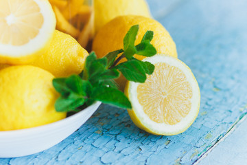 Yellow lemons with mint leaves, wooden background
