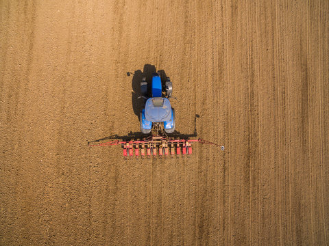 aerial view - Farmer with a tractor on the agricultural field sowing.  tractors working on the agricultural field in spring