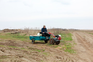 Obraz premium farmer on a small tractor with a trailer