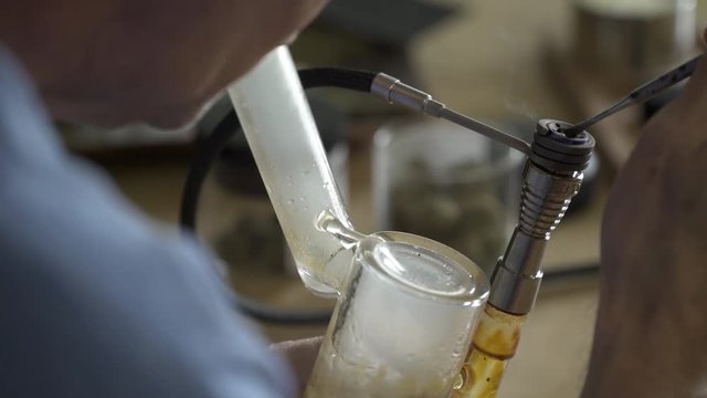 Close up of man smoking from dabbing pipe.