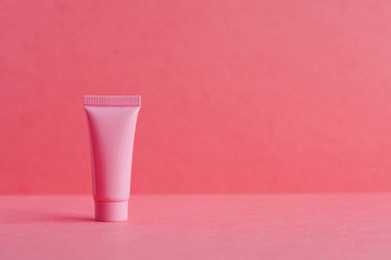 Pink cosmetic tube package on pink. Blank plastic container, simple packaging design template....