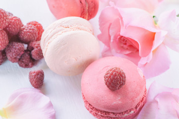 Macarons with raspberries, marshmallows on the background of beautiful flowers roses. Dessert close-up.