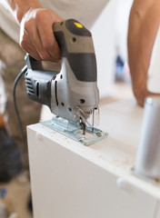A man cuts out a wooden board with a jigsaw