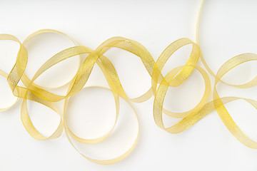 Shiny golden ribbon wound in spirals on white background. Backdrop for text or announcement