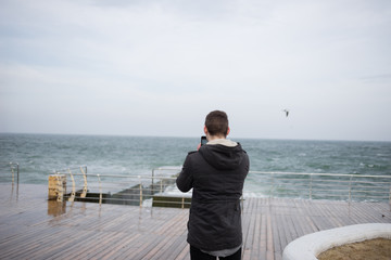 the guy is standing on the pier and taking a photo
