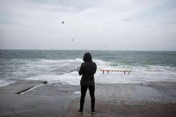 the guy is standing on the pier and admiring the sea