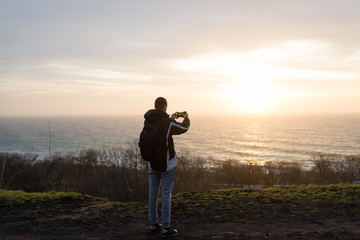 the guy takes a picture of the sunrise on the phone