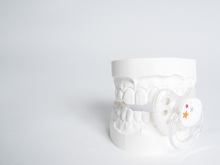 Minimizing the malocclusion caused by pacifiers, the gypsum tooth with the pacifier in front of the white background