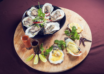 Opened oysters on ice seafood fresh and cooked served with sauce on wooden tray