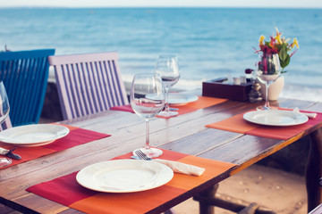 A romantic dinner in summer on a beach at sunset with two glasses of wine