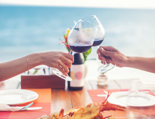 A romantic dinner in summer on a beach at sunset with two glasses of wine