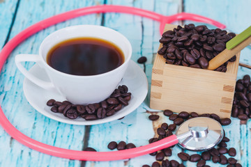 hot coffee cup with stethoscope on wood table.