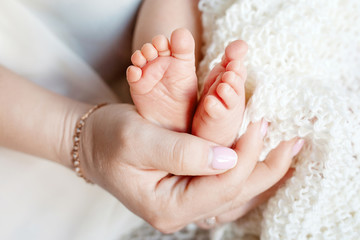 Baby feet in mother hands. Tiny newborn baby's feet on female shaped hands closeup. Mom and her child. Beautiful conceptual image of Maternity