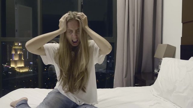 Young woman having headache and fainting in her room ion the bed.Health concept.