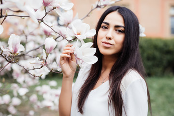 Young beautiful young woman near the blossoming spring tree