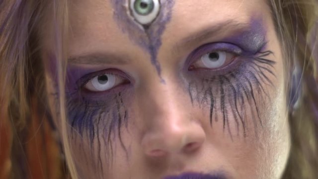 An alien woman with three eyes defiantly looks at the camera
