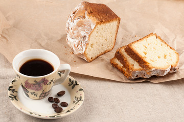 A Cup of coffee and a sliced cupcake on a linen tablecloth